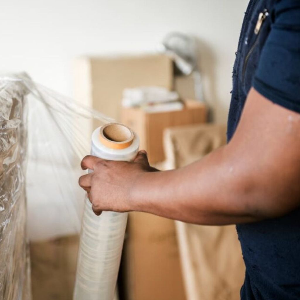Person sealing cardboard boxes with packing tape using a tape dispenser in a warehouse or packing area