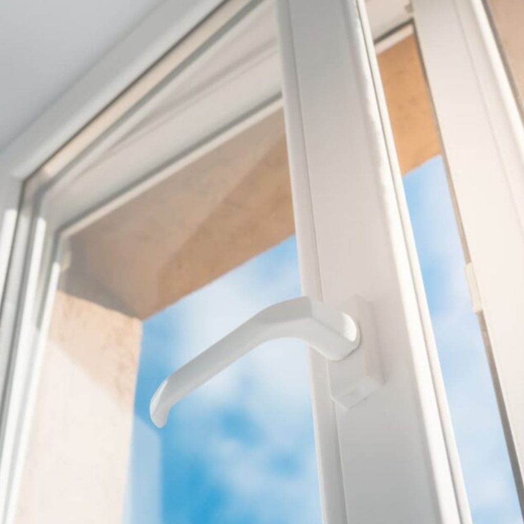 White UPVC window with an open lever-style handle, blue sky visible outside.