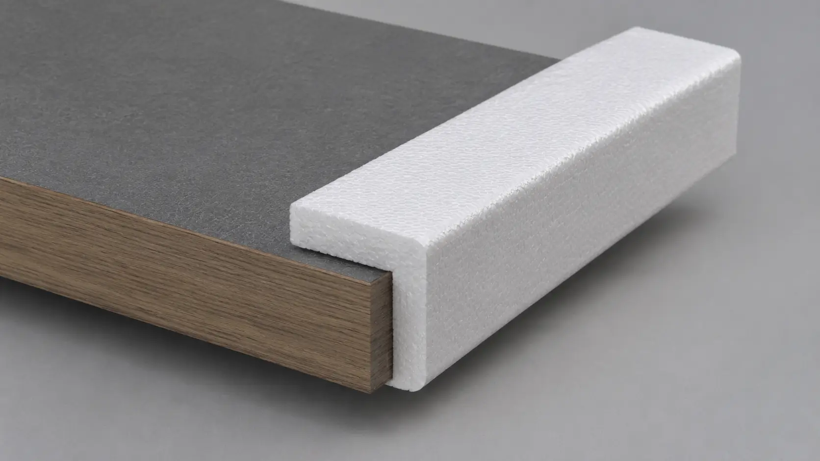 Cross-section of a flooring panel: wood veneer edge with gray top layer and a white foam edge protector.