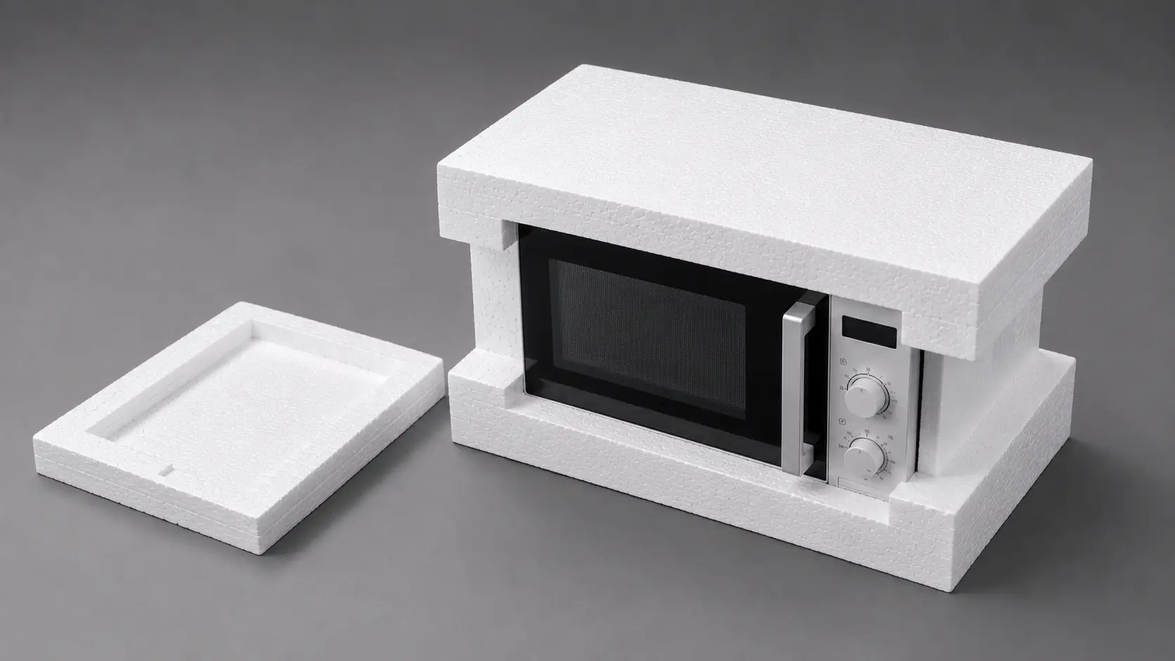 Foam model of a microwave with a black window, silver control panel, and open foam lid laid beside it on a gray background.